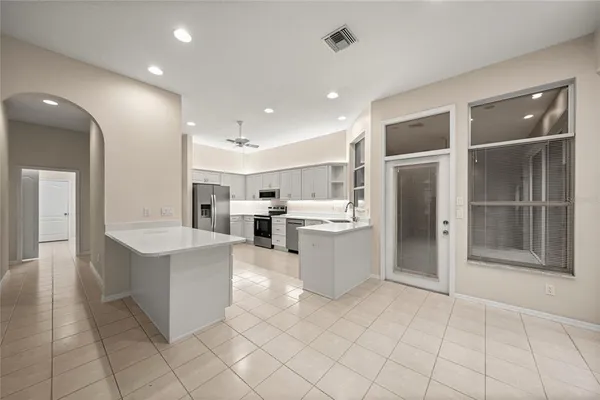 a large white kitchen with cabinets and chandelier