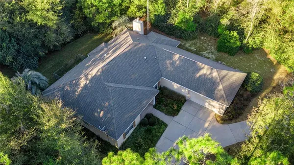 an aerial view of residential house with outdoor space and trees all around