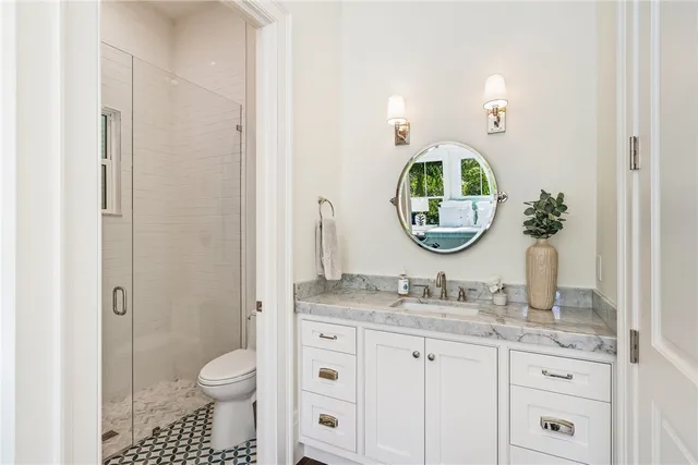 a bathroom with a granite countertop toilet a sink and a mirror