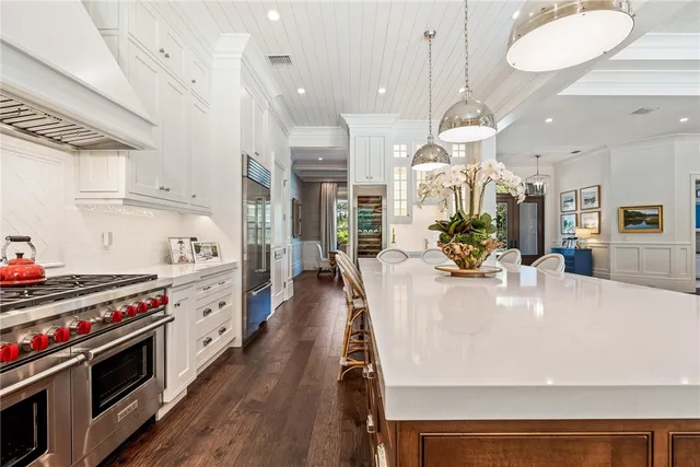 a large kitchen with stainless steel appliances a stove a table a chandelier and living room view