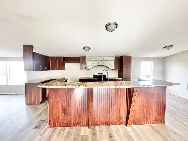 a kitchen with stainless steel appliances granite countertop a sink counter space and wooden floor