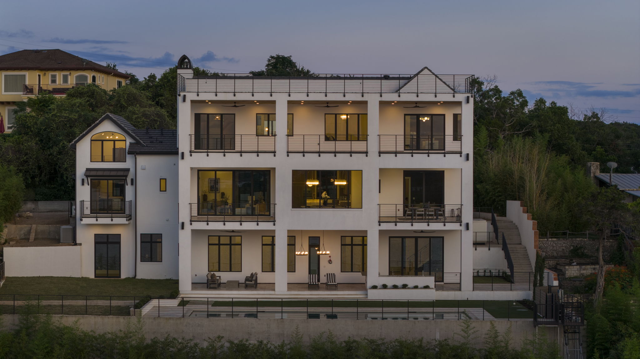 1496 Buffalo Gap Road Lakeway, TX 78734 - Photo 3 of 37 Dramatic multi-level home nestled into a hillside, showcasing expansive balconies and an inviting rooftop terrace.