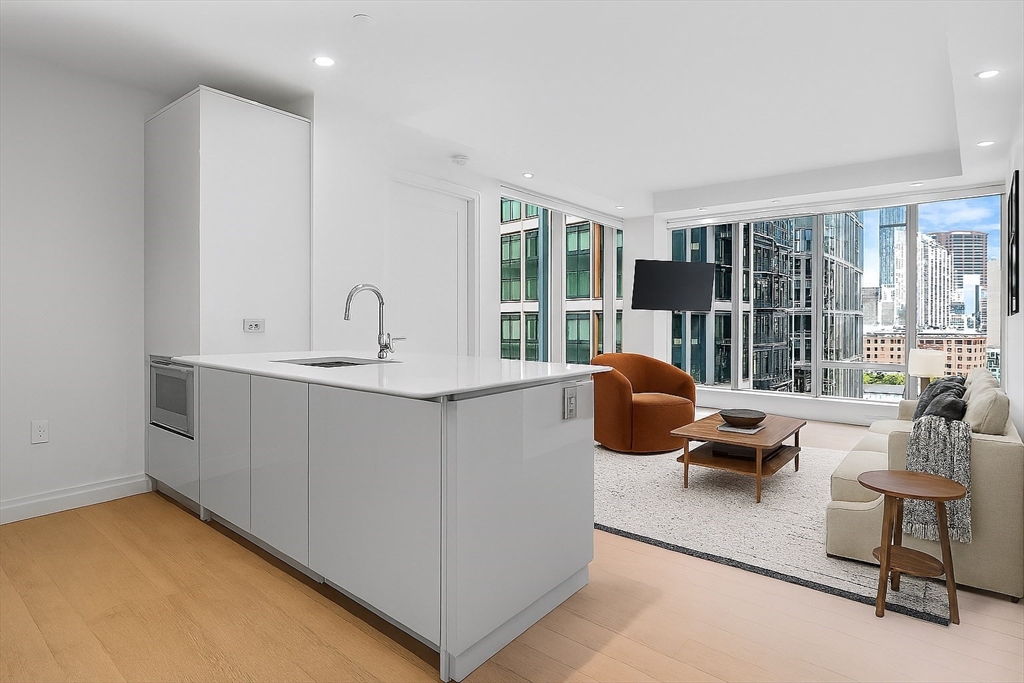 135 Seaport Boulevard, Unit 905 Boston, MA 02210 - Photo 3 of 21 a living room with furniture a large window and kitchen view