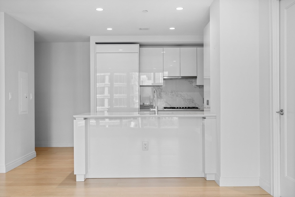 135 Seaport Boulevard, Unit 905 Boston, MA 02210 - Photo 8 of 21 a kitchen with kitchen island granite countertop white cabinets and stainless steel appliances