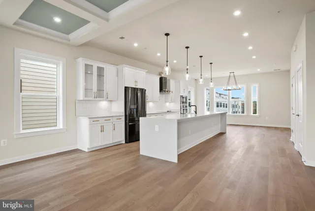 a large white kitchen with stainless steel appliances kitchen island a large counter top and a wooden floors