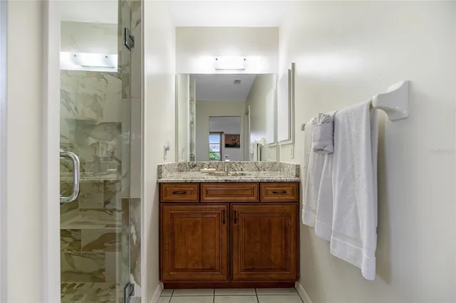 a bathroom with a granite countertop shower a sink and a mirror