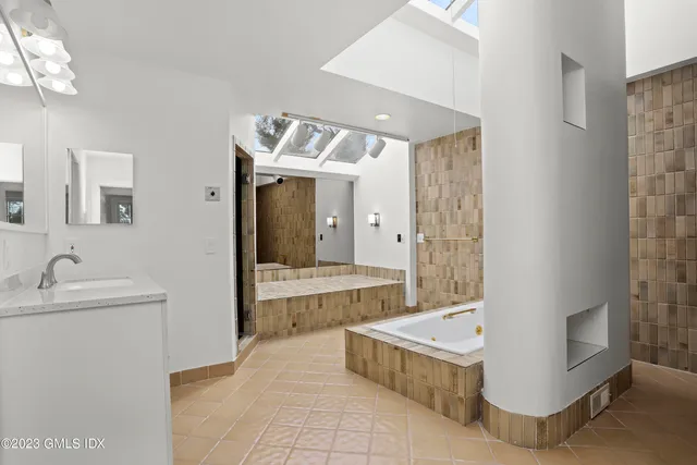 a bathroom with a tub sink and mirror