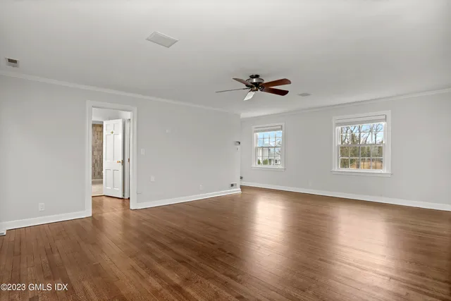 a view of an empty room with a window and wooden floor
