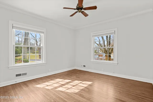 a view of an empty room with a window and wooden floor