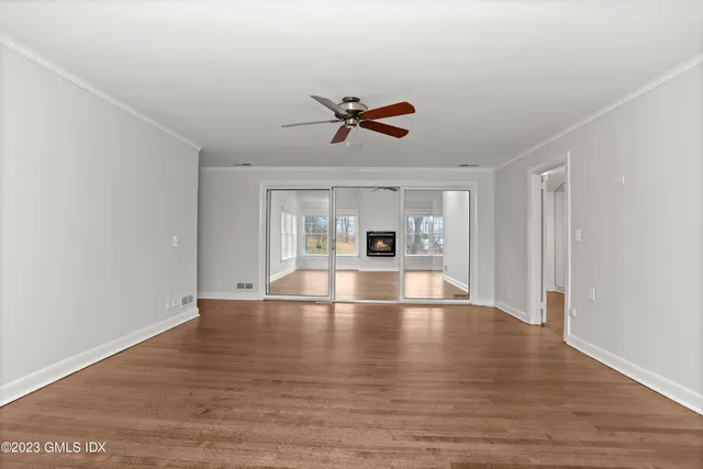 a view of empty room with wooden floor and fan