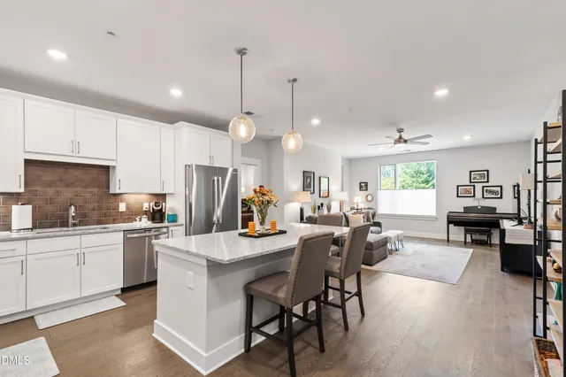 a kitchen with stainless steel appliances kitchen island granite countertop a stove a sink a dining table and chairs with wooden floor