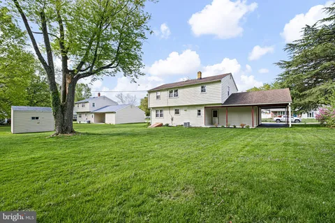 a view of a big house with a big yard plants and large trees