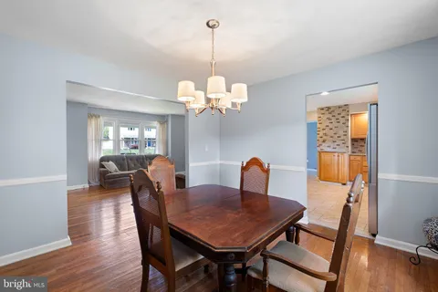 a dining room with wooden floor a chandelier a wooden table and chairs