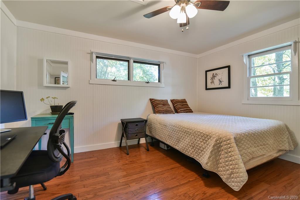 6295 Crabtree Road Clyde, NC 28721 - Photo 17 of 37 a bedroom with a bed a desk and chair with wooden floor