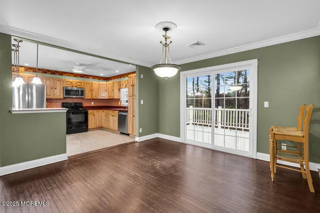 a view of an empty room with wooden floor and a kitchen