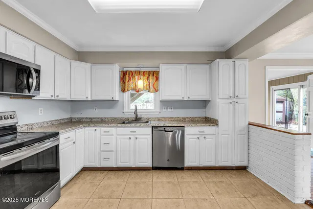 a kitchen with granite countertop white cabinets white stainless steel appliances and a sink