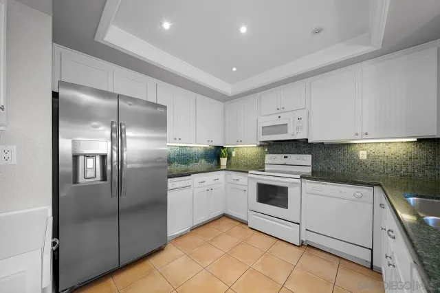 a kitchen with white cabinets stainless steel appliances and a counter space