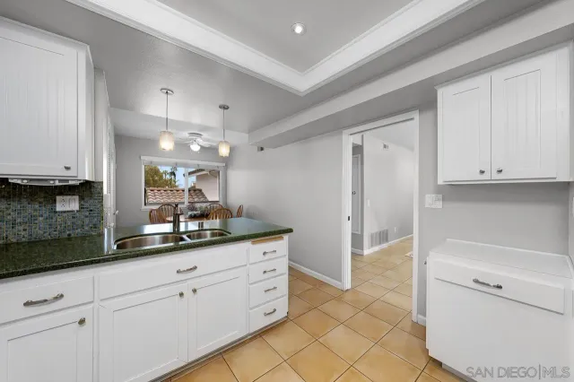 a kitchen with white cabinets and sink
