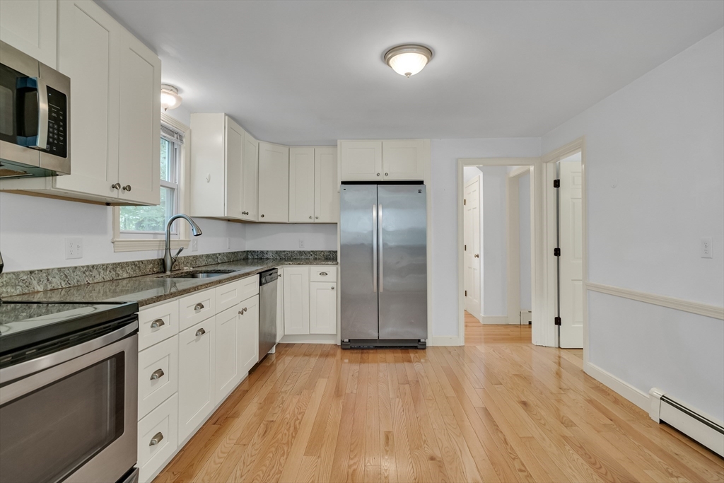 32 Dewey Road Lexington, MA 02420 - Photo 14 of 32 a kitchen with stainless steel appliances granite countertop a refrigerator a sink dishwasher and white cabinets with wooden floor