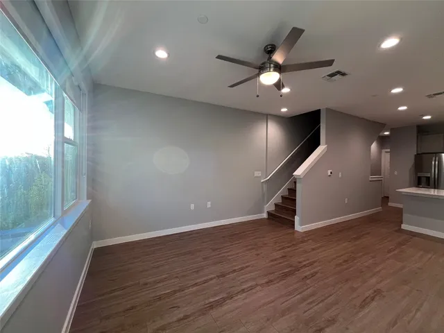 an empty room with wooden floor and a ceiling fan
