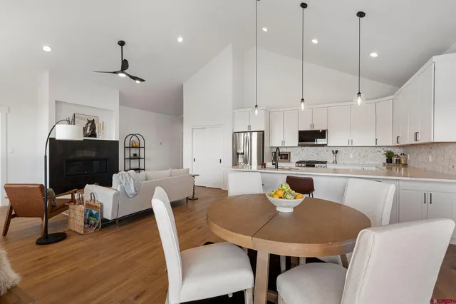 a kitchen with stainless steel appliances granite countertop a stove a refrigerator a kitchen island a dining table and chairs with wooden floor