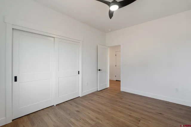 an empty room with wooden floor ceiling fan and windows