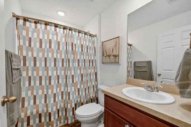a bathroom with a granite countertop sink toilet a mirror and shower curtain