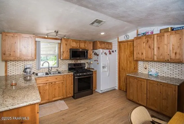 a kitchen with stainless steel appliances granite countertop a refrigerator stove and sink