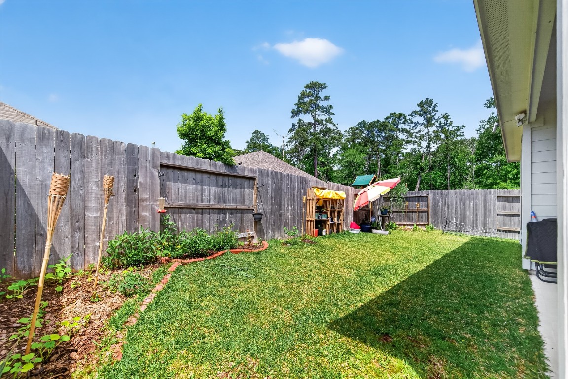 2739 Meadow View Lane Conroe, TX 77385 - Photo 44 of 50 a backyard of a house with table and chairs plants and large tree