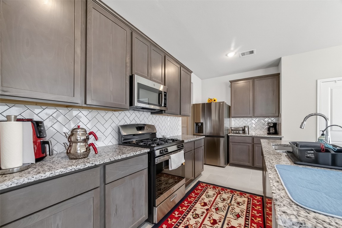 2739 Meadow View Lane Conroe, TX 77385 - Photo 6 of 50 a kitchen with granite countertop stainless steel appliances a sink a stove top oven a refrigerator and cabinets