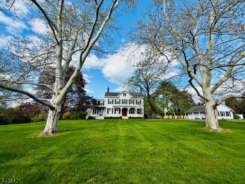 a view of a house with a big yard and large trees