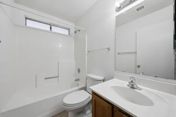 an empty room with a chandelier fan and windows