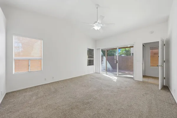 an empty room with windows and fan