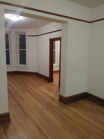 a view of an empty room with wooden floor and closet