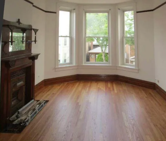 an empty room with wooden floor a fireplace and windows
