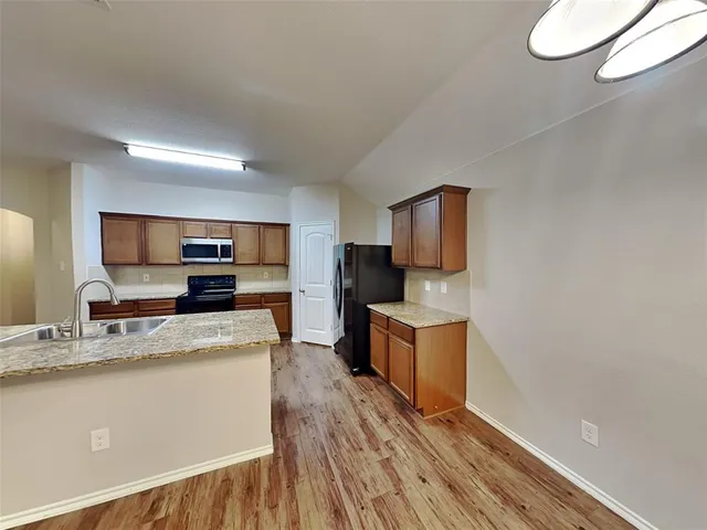 a large kitchen with a wooden floor and stainless steel appliances