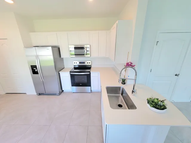 a kitchen with stainless steel appliances a sink a stove a microwave a refrigerator a counter top space and cabinets