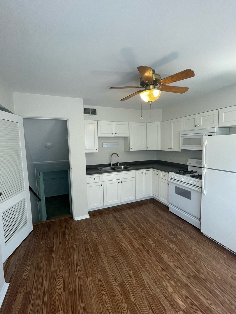 961 Spring Road Elmhurst, IL 60126 - Photo 12 of 24 a kitchen with granite countertop a refrigerator a stove a sink and white cabinets with wooden floor
