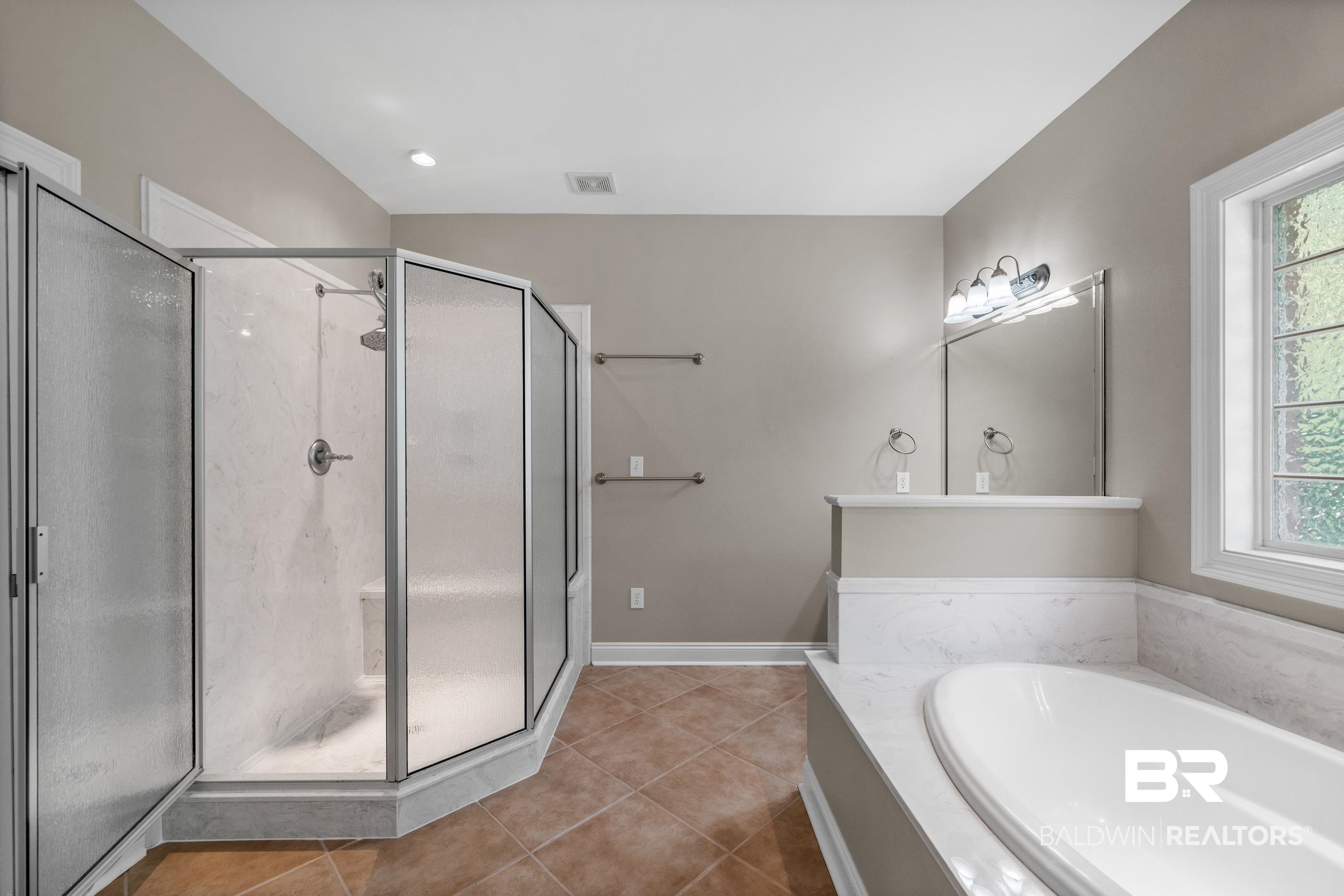 303 Savannah Circle Foley, AL 36535 - Photo 23 of 34 Spacious bathroom featuring a glass-enclosed shower with integrated seating, a separate soaking tub with a surrounding white-finish deck, and large-format tile flooring