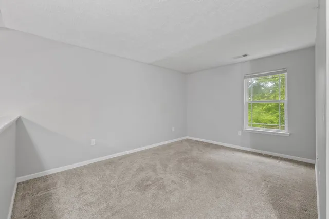 a view of an empty room with kitchen and a window