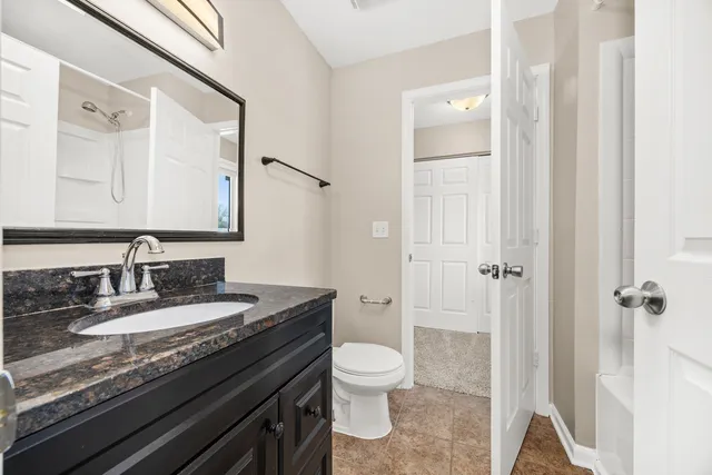 a bathroom with a granite countertop sink toilet a mirror and shower