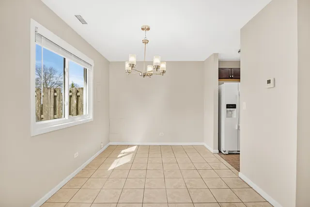 a view of an empty room with window and chandelier