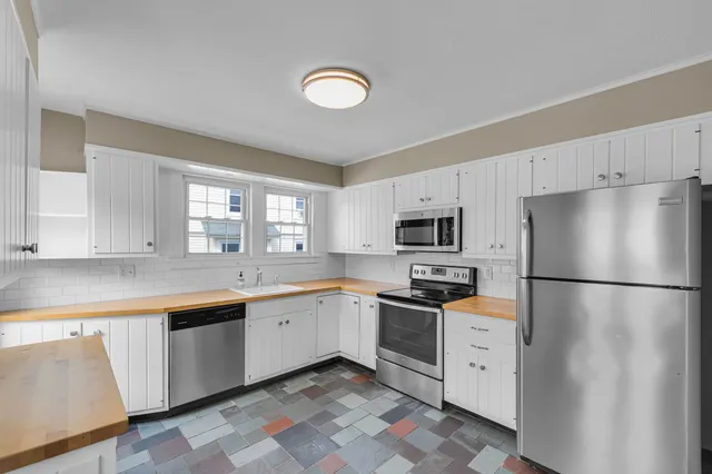 a kitchen with granite countertop appliances a sink and a refrigerator