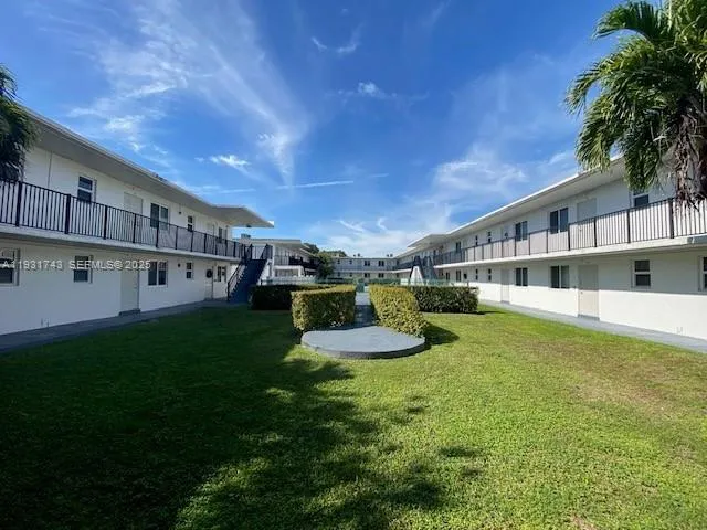 a view of a house with a big yard potted plants and large tree