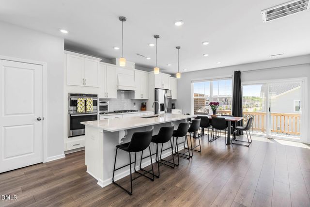 a kitchen with stainless steel appliances granite countertop a table chairs stove refrigerator and cabinets