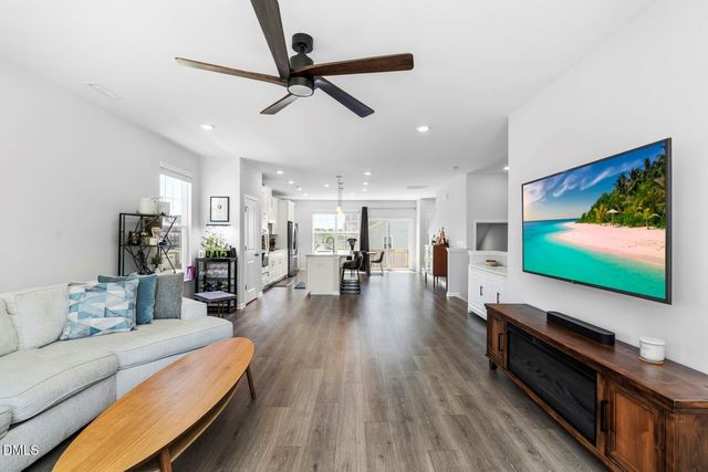 a living room with furniture and kitchen view with wooden floor