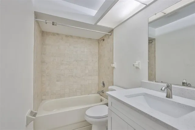 a bathroom with a granite countertop bathtub shower sink mirror vanity and toilet