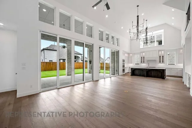 a view of an empty room with kitchen natural and wooden floor