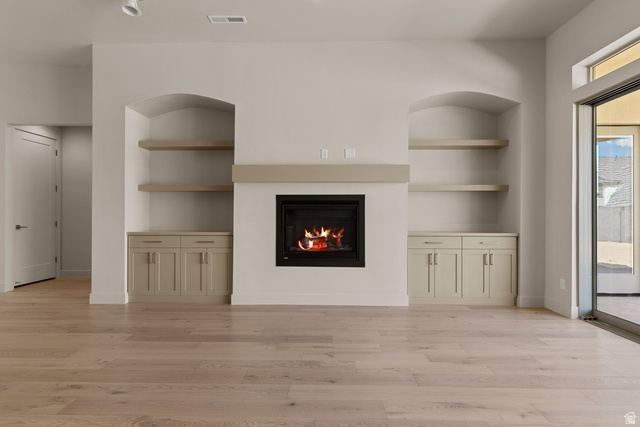 2955 East Rimrunner Drive St. George, UT 84790 - Photo 12 of 35 Central fireplace with hearth, flanked by arched built-in shelving units, lower cabinetry, and wood-finish flooring