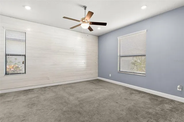 en empty room with windows and ceiling fan